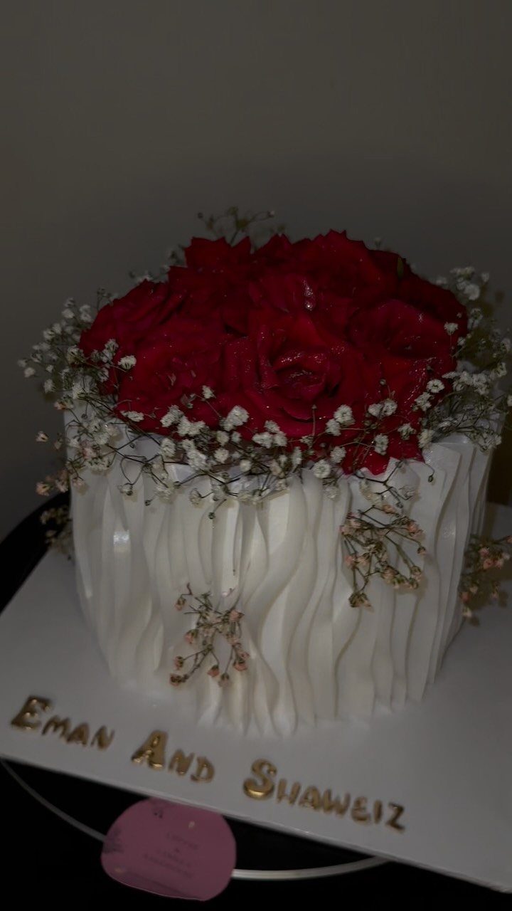 White textured wedding cake topped with red roses and baby's breath flowers