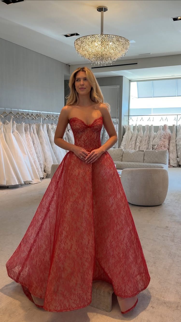 Woman wearing a strapless red lace wedding dress in a bridal boutique setting