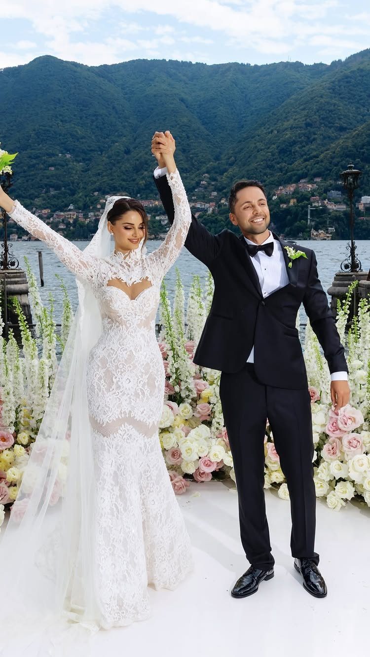 Bride and groom holding hands by a lake with mountains in the background