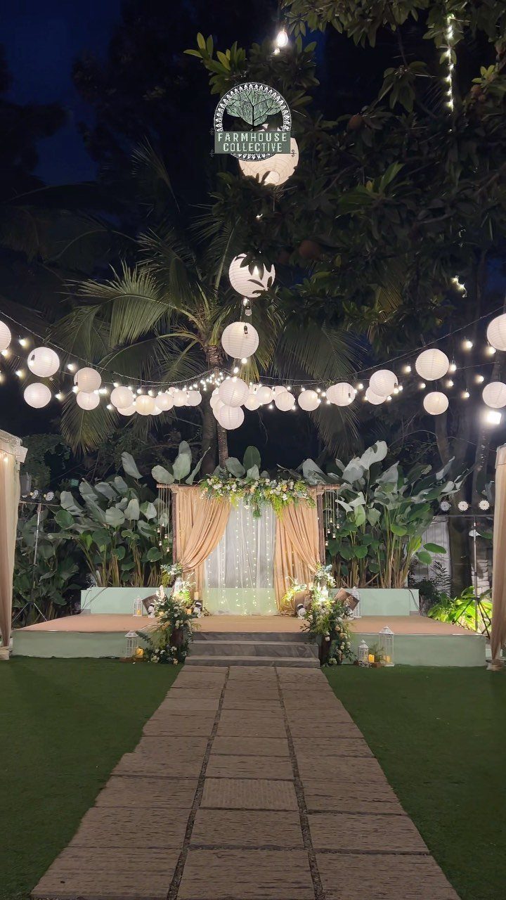 Outdoor wedding altar with peach curtains and white lanterns under palm trees