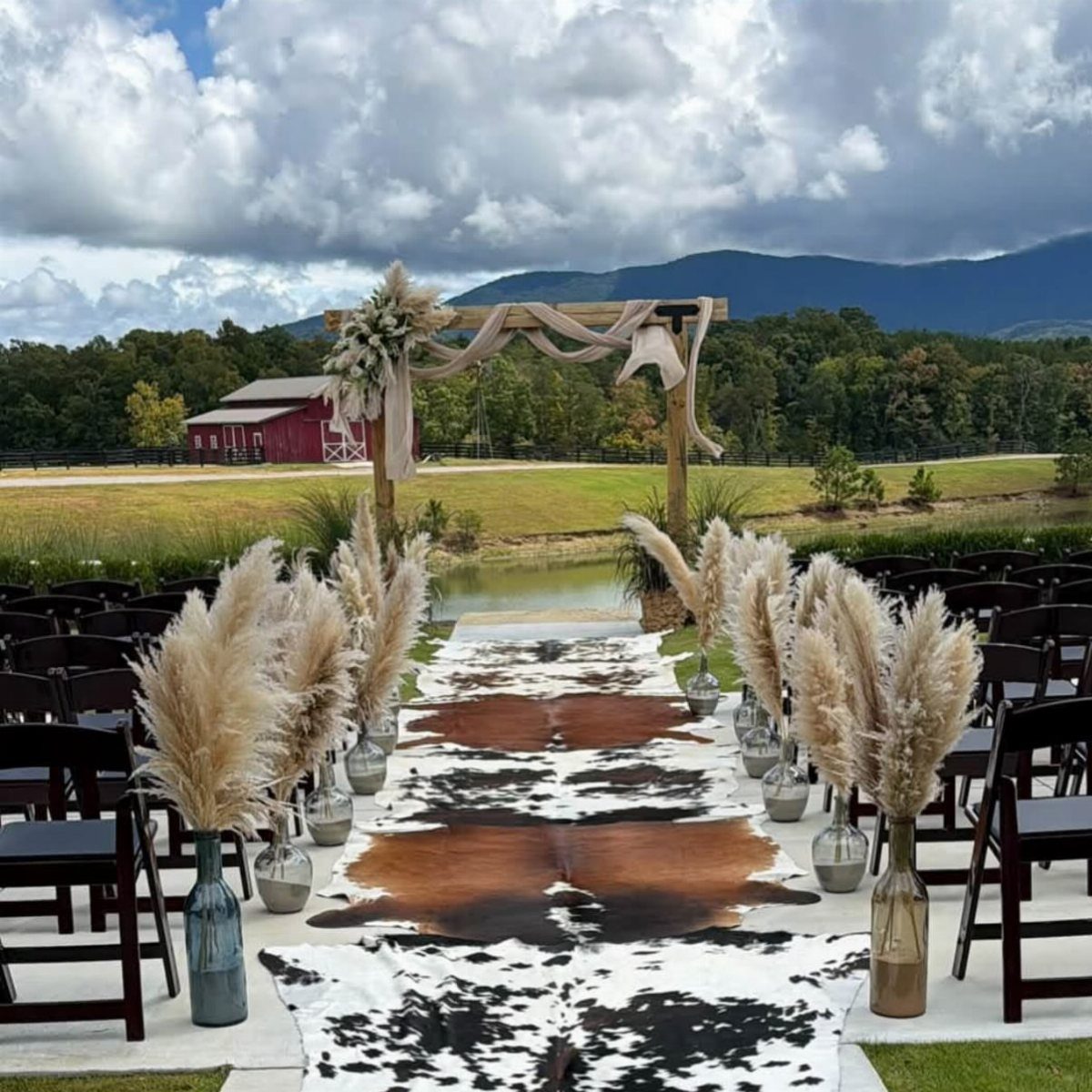Cowhide rugs forming an aisle runner for an outdoor western wedding ceremony.
