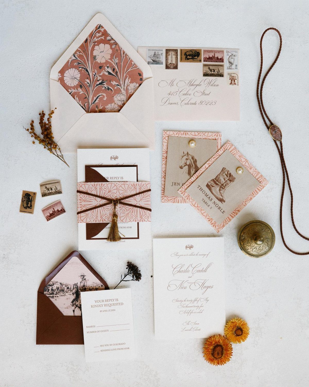 Western wedding invitation suite with horse illustrations, floral envelopes, and rustic leather accents.