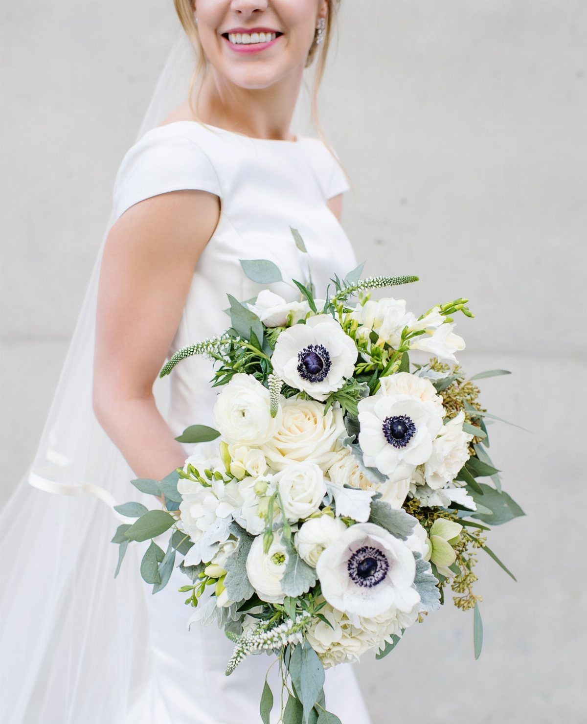 Bridal bouquet with white anemones, white roses, and green eucalyptus leaves.