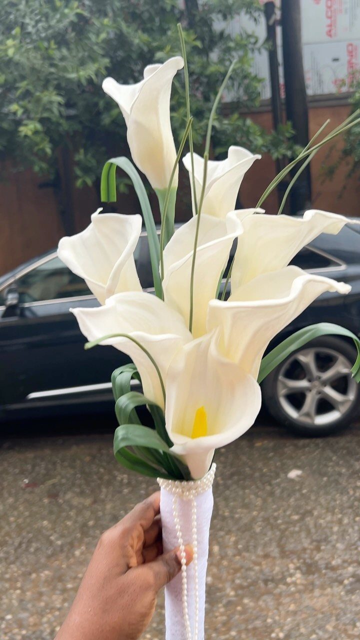 White calla lily wedding bouquet wrapped in white ribbon with pearl accents.