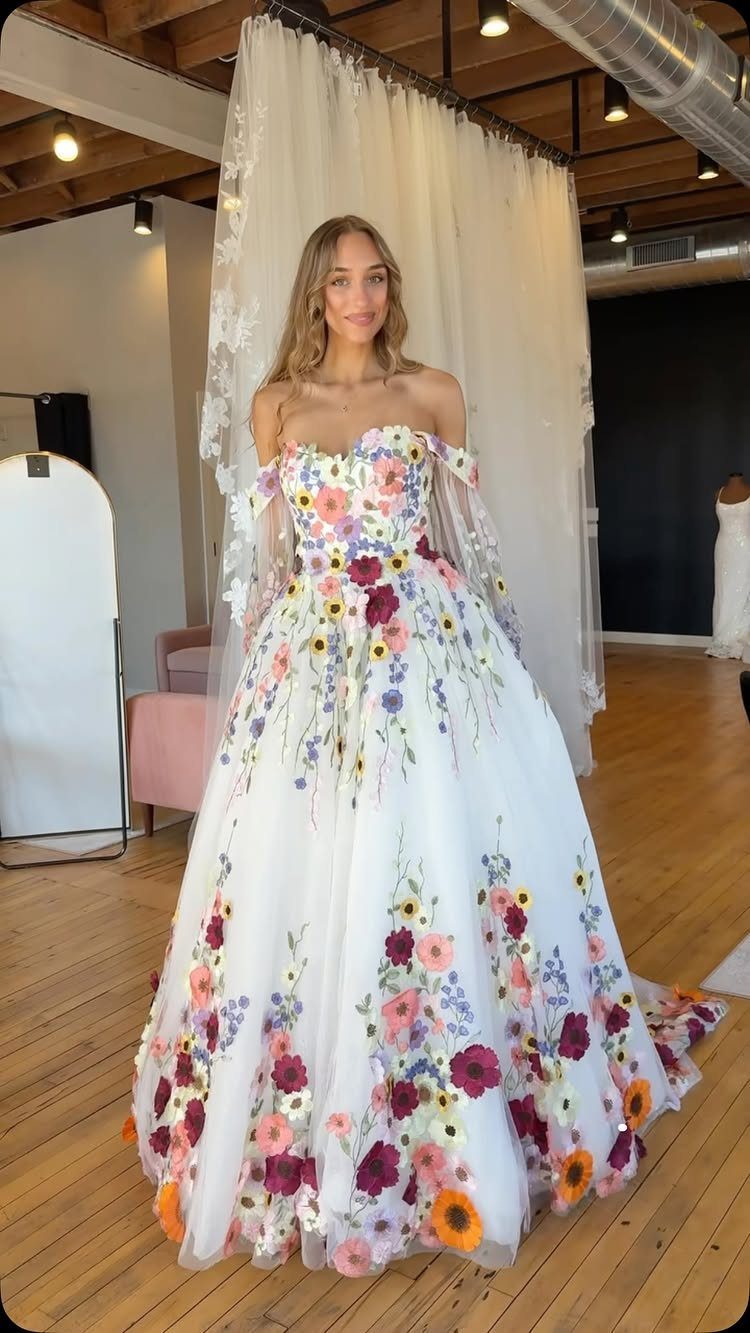 Woman in a white wedding dress with colorful wildflower embroidery in a boutique