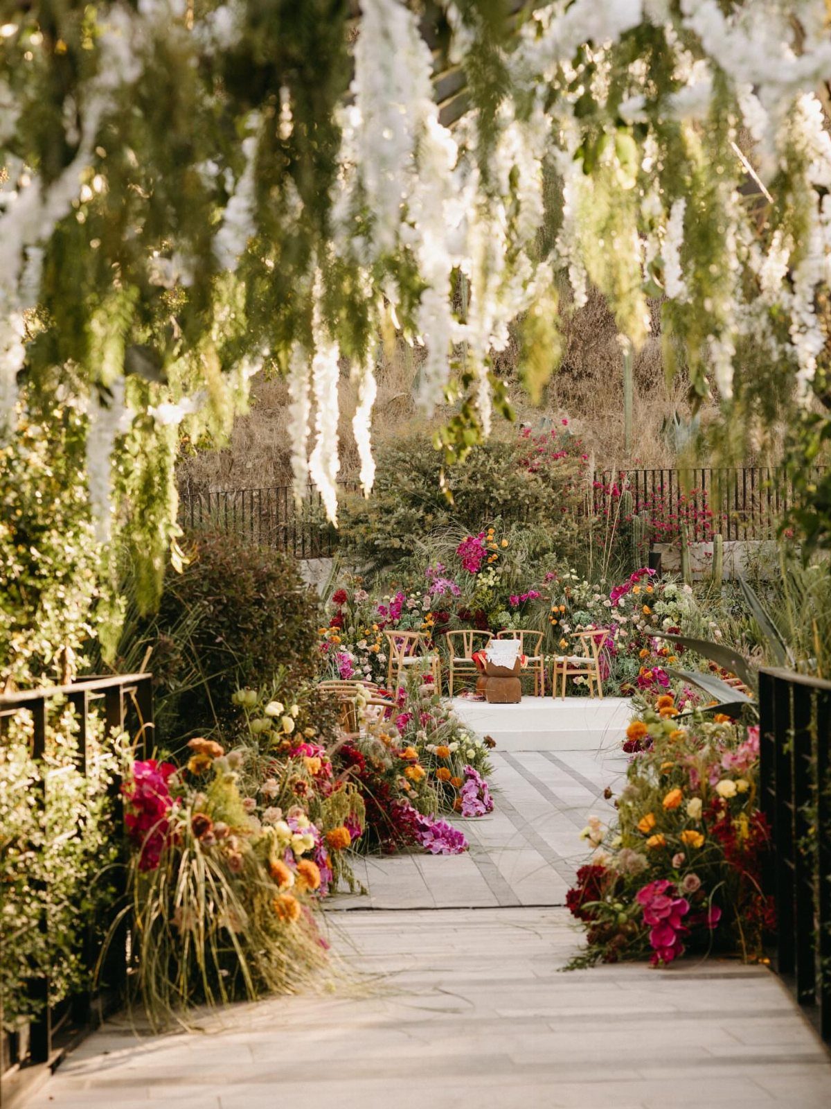 Colorful wildflower arrangements lining a garden path leading to a wedding ceremony setup.