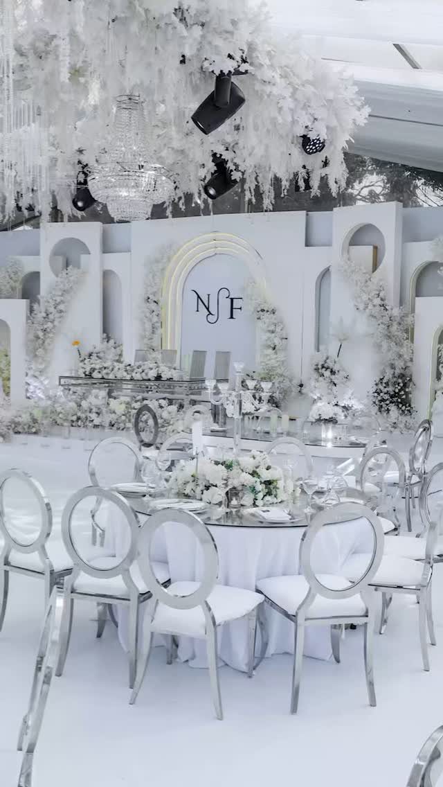 White wedding reception tables with silver chairs and white floral decorations.