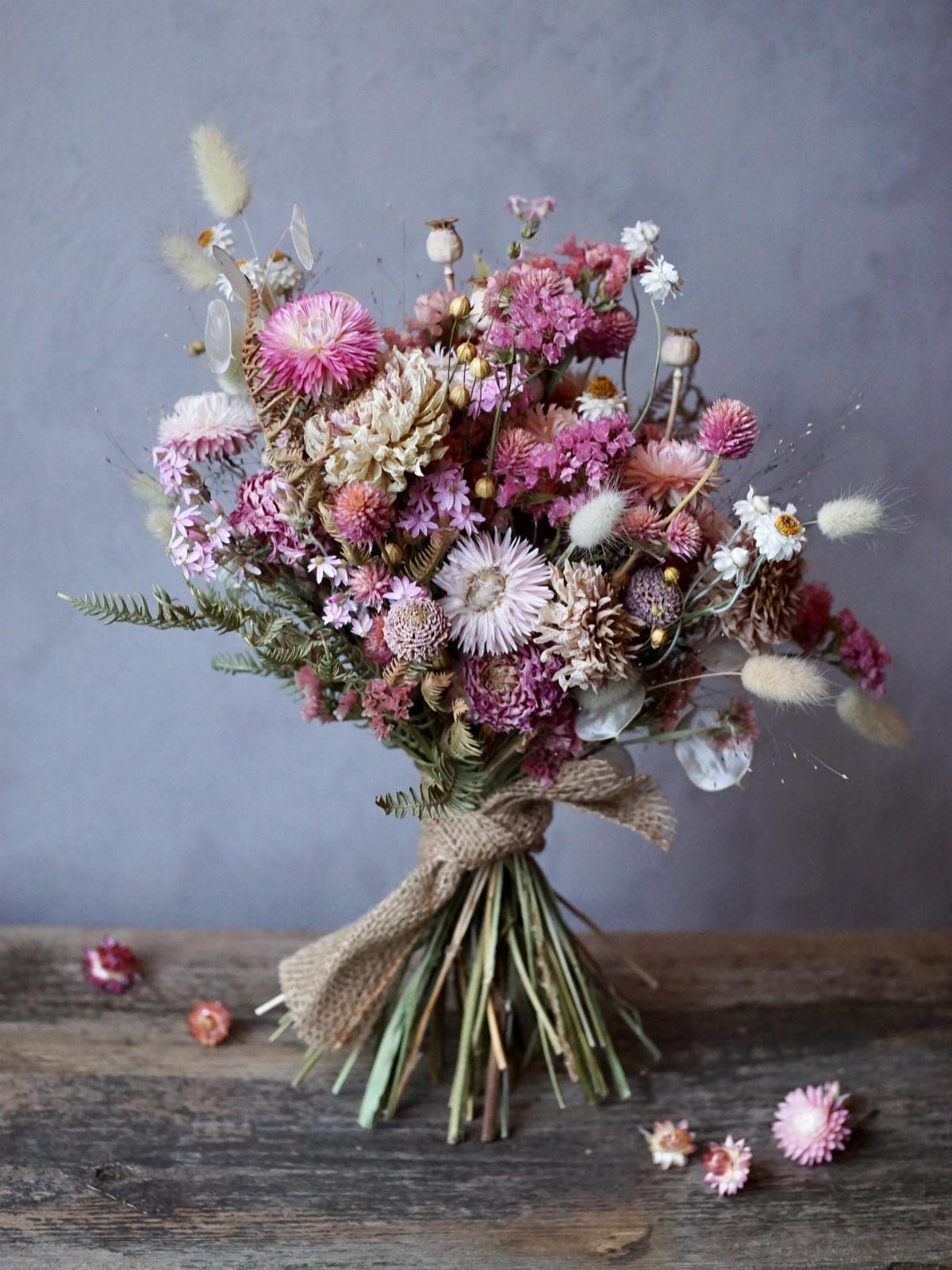 Dried flower bouquet with pink and white blooms tied with burlap ribbon.