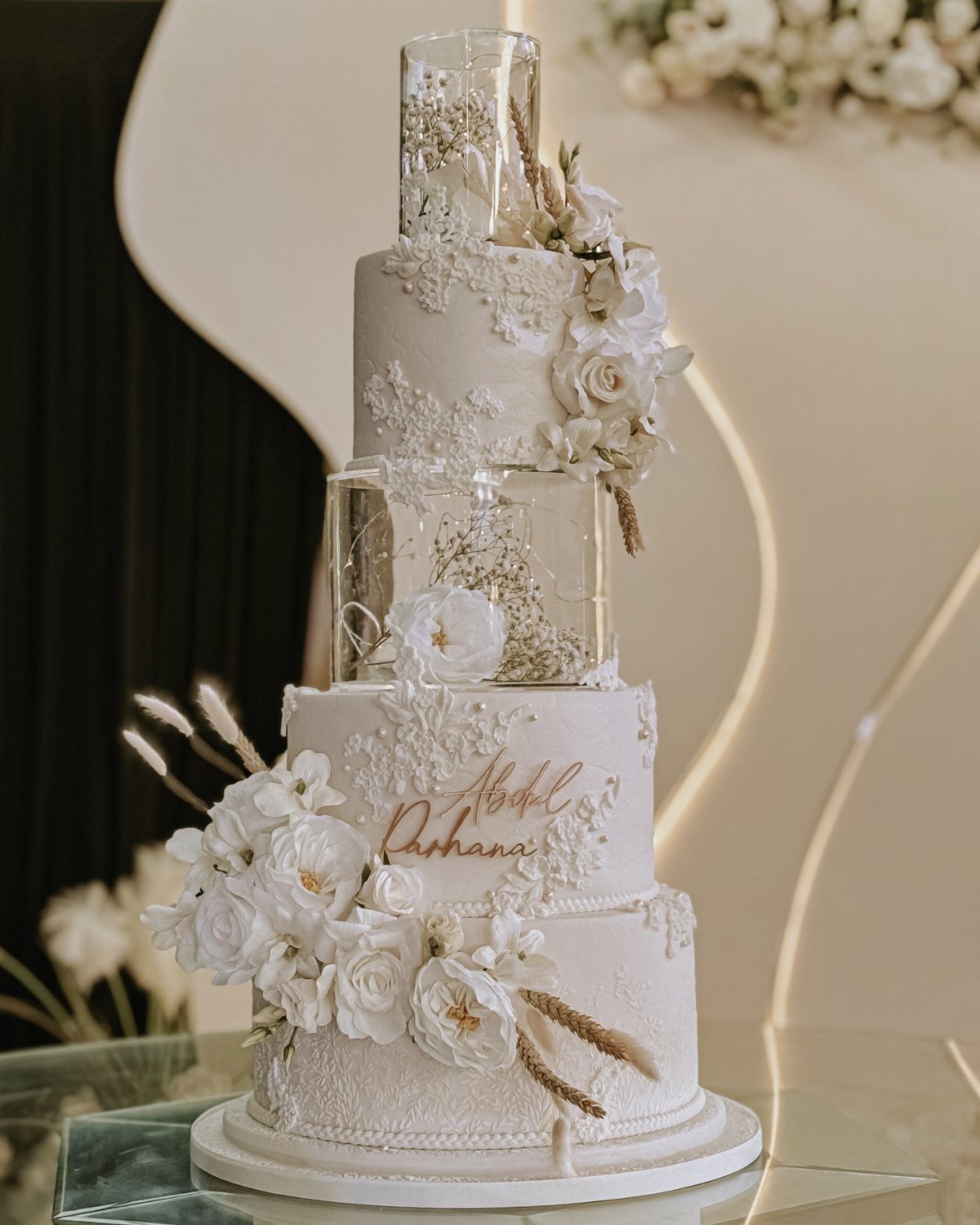 Multi-tiered white wedding cake with floral decorations and clear glitter-filled acrylic spacers.